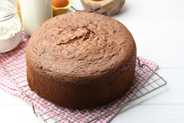 Tasty chocolate sponge cake and ingredients on white wooden table, closeup