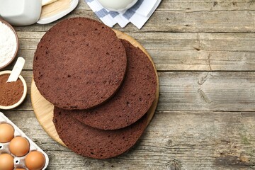 Cut chocolate sponge cake and ingredients on wooden table, flat lay. Space for text