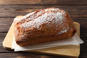 Tasty sponge cake with powdered sugar on wooden table, closeup