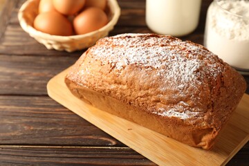 Tasty sponge cake with powdered sugar on wooden table, closeup