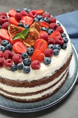 Delicious chocolate sponge cake with berries on grey table, closeup