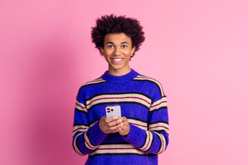 Photo of smart clever man guy with wavy hair dressed knitwear sweater holding smartphone in hands isolated on pink color background