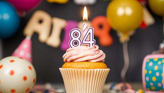 Birthday cupcake with burning lit candle with number 84. Number eighty-four for eighty-four years or eighty-fourth anniversary.