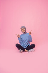 A cheerful young woman is posing confidently in vibrant sportswear against a pink backdrop