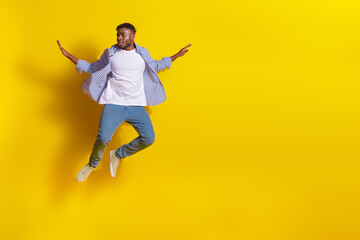 Obraz premium Full length photo of attractive funny guy wear plaid shirt jumping high flying emtpy space isolated yellow color background