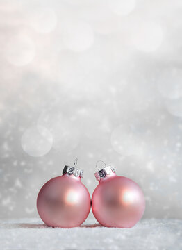 Beautiful pink Christmas balls, snowflakes on snow on winter background.