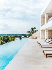 Fototapeta premium Luxurious infinity pool overlooking lush greenery at a modern villa during a cloudy day