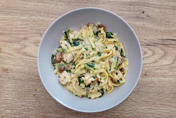 A delicious homemade dinner of pasta, chicken and sauce lying on a plate on the table.