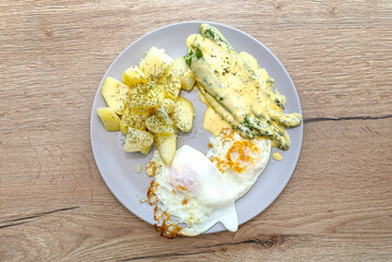 Breakfast made of fried eggs with green asparagus in Hollandaise sauce and potatoes.