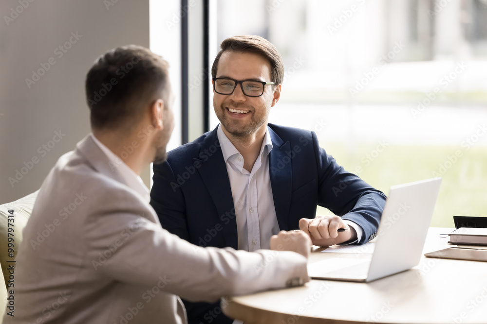 Poster successful handsome businessman meeting with partner, talking to colleague at laptop. happy coworker