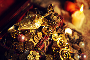 Precious golden magic lamp and treasure chest on sand.