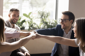 Cheerful happy office friends making fist bump group gesture, raising team spirit, celebrating success, teamwork achieve, successful business project startup, enjoying friendship