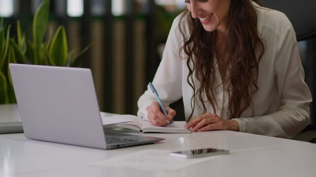 Smiling happy Caucasian woman business worker office manager girl female lady businesswoman planner online studying class learn exam course video call laptop conference chat write notes notebook tasks