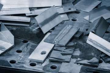 A pile of metal pieces with a few of them having holes in them. The pile is on a table. metalworking concept background