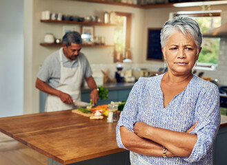 Mature woman, angry and crossed arms in house for fight, argument and marriage conflict with partner. Female person, frustrated and unhappy in kitchen for pride, disappointed and cooking disagreement