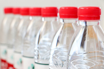 Close up of clear plastic bottles of water with red caps in a line. Selective focus. Drinking water, healthy lifestyle, hydration concept.