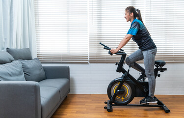 Asian female beautiful women cycle at home using stationary exercise bike, healthy lifestyle ...