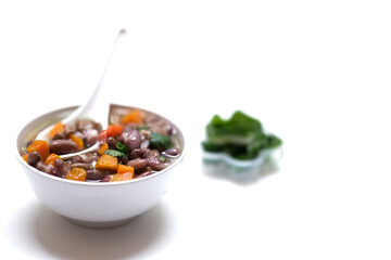 Sup daging kacang merah, clear soup with beef slices, red bean and vegetables. Served in bowl on white background. Selected focus