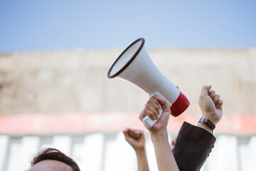 An activist fervently speaks into a megaphone at a vibrant rally, urging for change and support