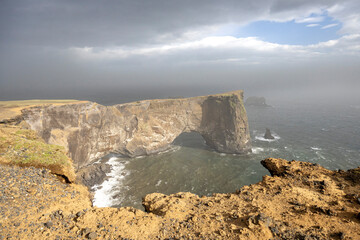 Dyrhólaey cliffs with arch from the promenade on a stormy day, South Iceland
