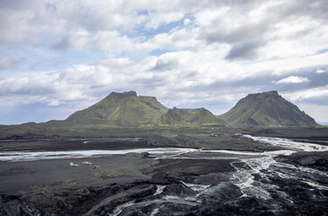 volcanic outwash plain with glacial river and green mountain range, Katla ICe Cave, Iceland