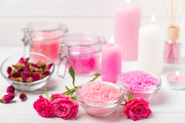 Sea salt for bath with aroma and rose flowers on textured wooden background. Pink sea salt. Spa treatments. Natural salt with herbs and essential oils. skincare concept. Meso for text. Copy space