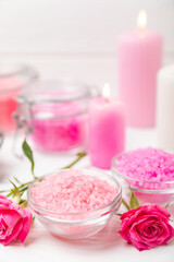 Sea salt for bath with aroma and rose flowers on textured wooden background. Pink sea salt. Spa treatments. Natural salt with herbs and essential oils. skincare concept. Meso for text. Copy space