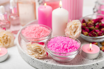 Sea salt for bath with aroma and rose flowers on textured wooden background. Pink sea salt. Spa treatments. Natural salt with herbs and essential oils. skincare concept. Meso for text. Copy space