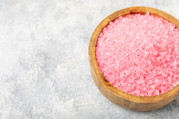 Sea salt for bath with aroma and rose flowers on textured wooden background. Pink sea salt. Spa treatments. Natural salt with herbs and essential oils. skincare concept. Meso for text. Copy space