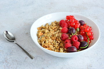a bowl of cereal with raspberries and a spoon