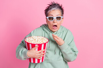 Photo of impressed attractive lady wear khaki hoodie watch movie eat pop corn empty space isolated pink color background