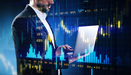 Businessman analyzing forex data on laptop with digital financial graphs overlay on dark background.