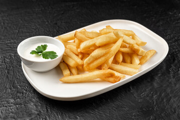A plate of french fries with a white sauce on the side