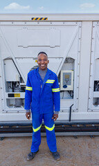 portrait of single african man worker industrial setting outdoors in front of a mobile air conditioner cooling unit,