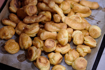 Golden Choux Pastries Fresh from the Oven Resting on a Baking Tray in a Warm Indoor Kitchen Under Soft Ambient Lighting