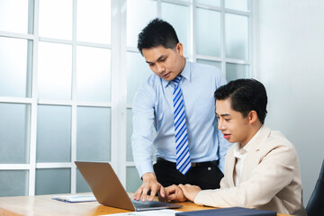 Obraz premium Professional Asian businessmen partner working together in an office, planning strategy, creative thinking innovation ideas, assisting helping each other with good teamwork communication skills.