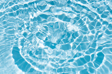 Blue water with ripples on the surface. Defocus blurred transparent blue colored clear calm water surface texture with splashes and bubbles. Water waves with shining pattern texture background.