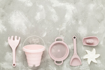 Cute toys for playing with sand on concrete background, top view