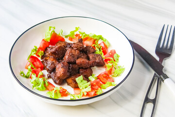 a plate of chopped beef steak with salad