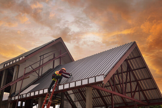 Construction worker installing metal sheets on a roof, Thailand