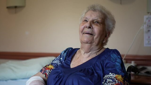Portrait of elderly woman in muumuu with bruised face black eye holding up cast sitting in wheelchair in rehabilitation facility.