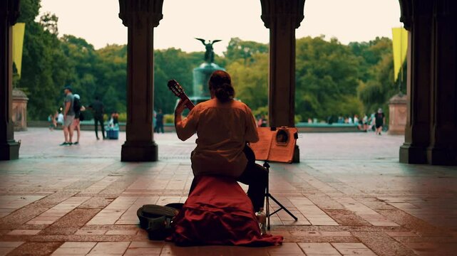 Street musician guitarist playing in archway tunnel late evening street lights slow motion