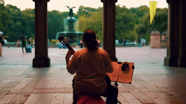Street musician guitarist playing in archway tunnel late evening street lights slow motion