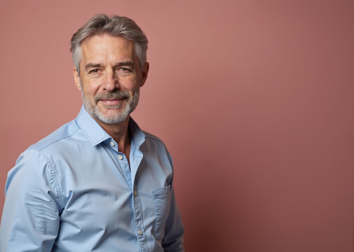 Mature Man with Confident Smile Posing Against Pink Background with Copy Space