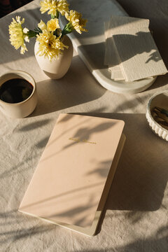 Overhead view of a weekly planner on a table with a cup of black coffee, a vase filled with flowers and assorted ceramics
