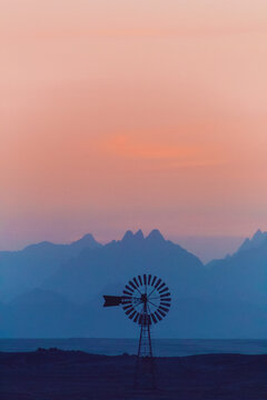 Silhouette of a traditional old-fashioned metal windmill by the sea at sunset, Hurghada, Red Sea coast, Egypt