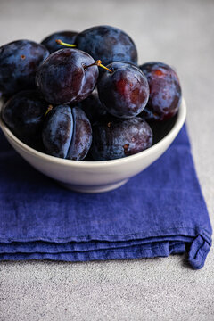 Close-up of a Bowl of organic ripe black plums on a folded napkin