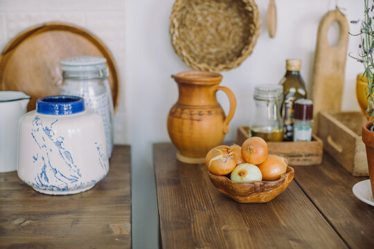 Bowl of onions on a kitchen table with assorted jugs, bowls and cookware