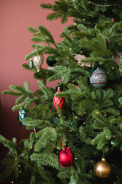 Close-up of a assorted Christmas baubles on a Christmas tree with a pink background