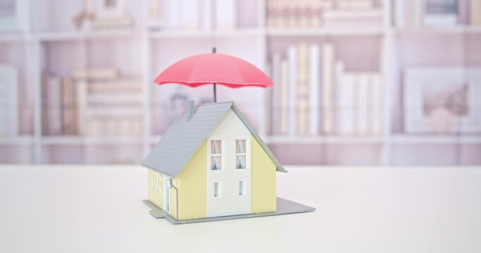 Protection from mortgage foreclosure and land contract forfeiture, business mortgage loan and real estate property insurance concept : Red umbrella covers or protects a residential home model.